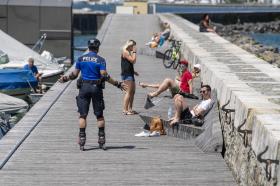 Cop on rollerskates talking to sunbathers