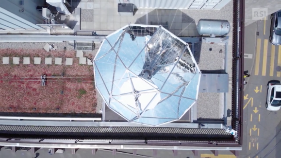 Dach eines Industriegebäudes in der Senkrechten; man erkennt eine grosse Parabolantenne und eine Art Zisterne