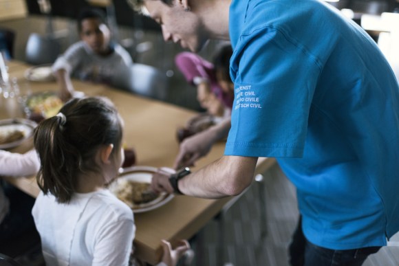 Un joven ayuda a una niña con la comida