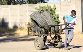 Jeune Africain traînant une charrette avec deux pneus