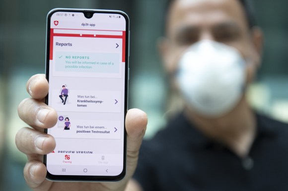 Homem de máscara mostra tela de celular com aplicativo de rastreamento
