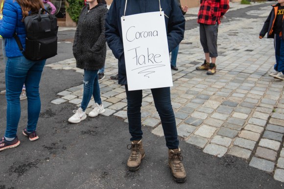 A protester wearing a Corona Fake placard