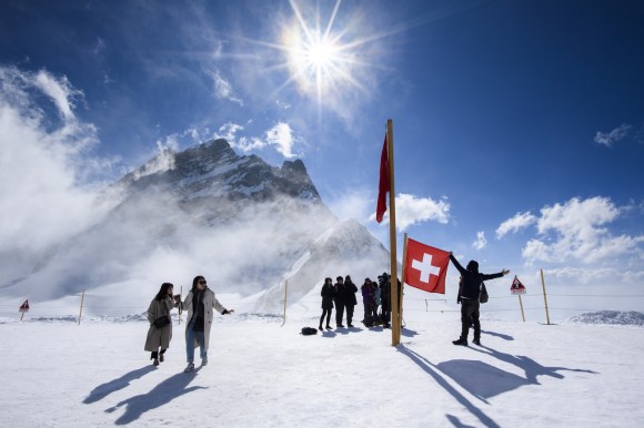 Grupo de turistas en estación de esquí y con la bandera suiza