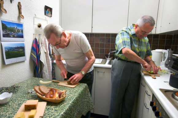 двое немолодых мужчин на кухне готовят завтрак