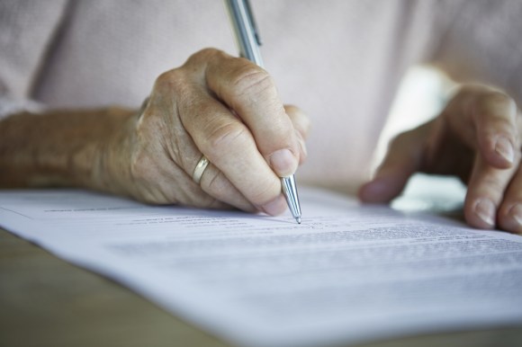 Imagen parcial de una persona mayor firmando un documento