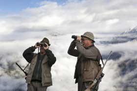 Los cazadores en los Alpes suizos con prismáticos para avistar aves