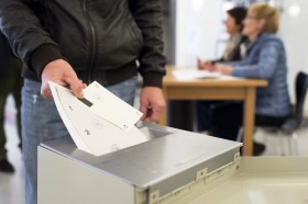 un uomo infila la scheda elettorale nell urna