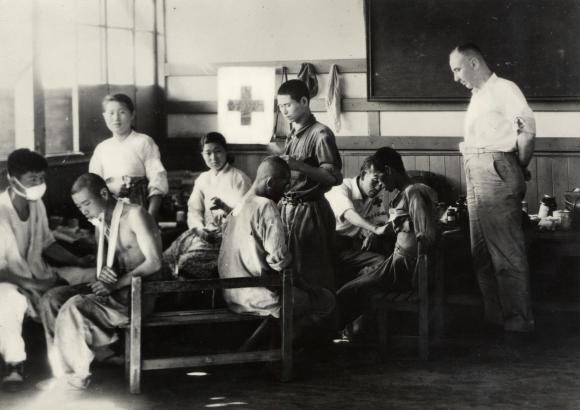 صورة بالأبيض والأسود لجرحى وممرضين في مستوصف أنشأته اللجنة الدولية للصليب الأحمر داخل معسكر اعتقال في كوريا الجنوبية