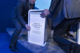 Hombres trasladan un podio con el logotipo del Foro Económico Mundial de Davos