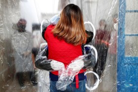 People hugging through a plastic curtain