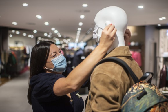 Shop assistant putting a mask on a mannequin