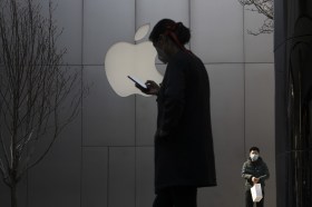 A woman uses her phone near the Apple store in Beijing.