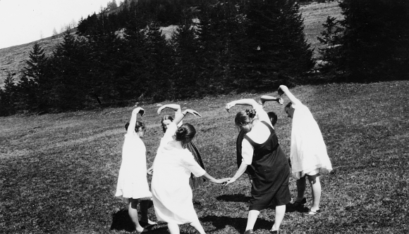 Moças dançando em roda num prado