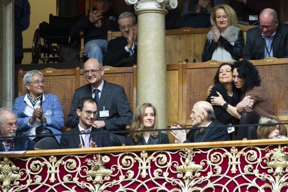Personas aplaudiendo en la tribuna de visitantes del Parlamento suizo