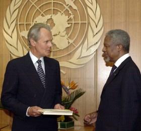 رجلان يتحادثان وفي الخلفية شعار الأمم المتحدة
