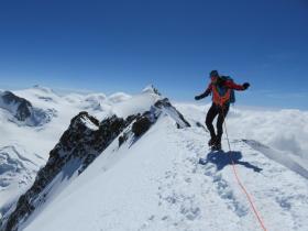 Climber attached to a rope on a snowy mountain summit