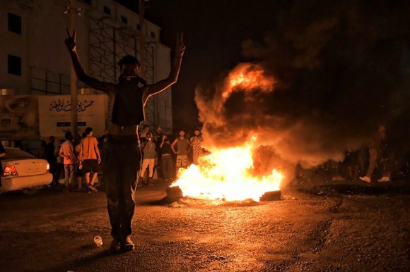 شبان محتجون متجمعون ليلا حول نيران مشتعلة وسط شارع