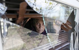 A woman inspects her house damaged by shrapnel in the village of Staromihailovka, Donetsk.