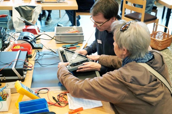Repair expert helping a customer with a damaged product at a Repair Cafe