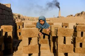 Girl collecting bricks as a labourer at a brick factory in India