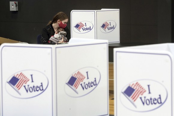 امرأة تحمل رضيعها وتقوم بالادلاء بصوتها داخل مكتب اقتراع