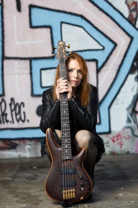 portrait de Lea accroupie derrière sa guitare
