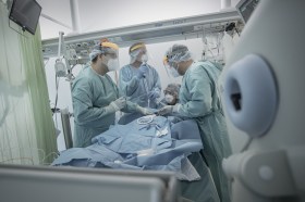 Varios médicos con material quirúrgico atienden a un paciente.