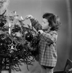 Little girl lighting candles on Christmas tree