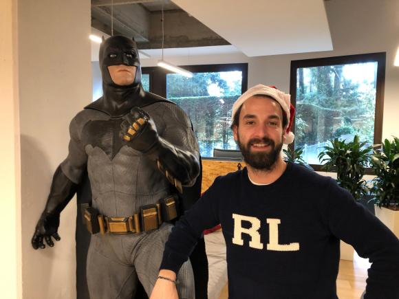 Homem com gorro de Papai Noel e uma estátua do Batman