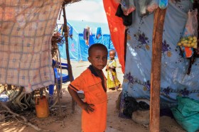 طفل صغير من الصومال داخل خيمة ينظر إلى عدسة المصور