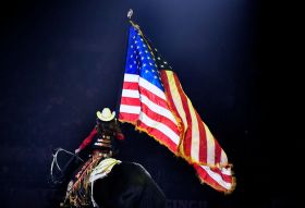 امرأة تركب فرسا وتحمل العلم الأمريكي