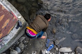 Un hombre se lava la cara con agua del río