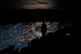 Una persona de pie cerca de un río, en la noche
