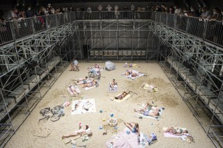Escena de obra de teatro: personas acostadas sobre supuesta playa