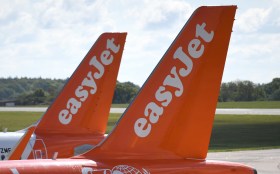 طائرتان بألوان برتقالية وبيضاء رابضتان فوق أرضية مطار
