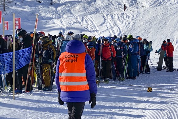 skiers and snowboarders queue at a ski lift in Verbier