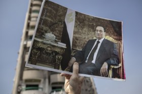 يدٌ رجل ترفع صورة للرئيس المصري الراحل حسني مبارك