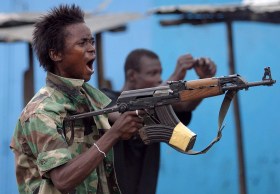 Escena de guerra en Liberia. En primer plano un hombre con un fusil.