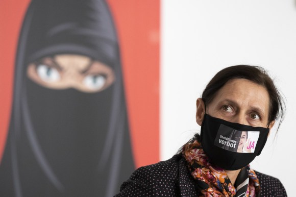 Une députée UDC masquée devant l affiche de campagne, montrant une femme en niqab