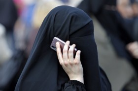 Woman with face covered makes telephone call