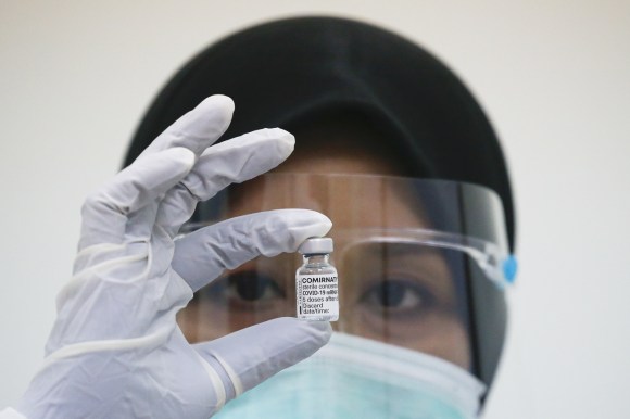Una mujer muestra una ampolleta de vacuna