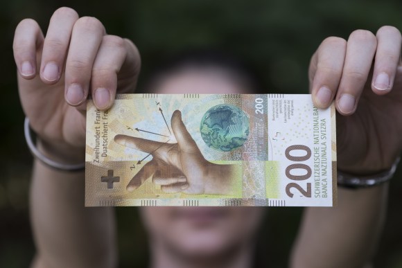 يدا فتاة تعرضان ورقة نقدية من فئة 200 فرنك سويسري