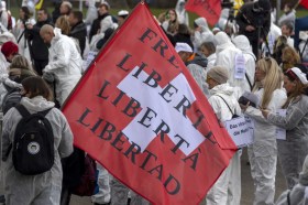 Schweizer Flagge und Demonstranten in weissen Overalls