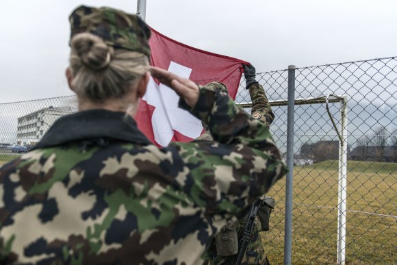 Female soldier saluting Swiss flag