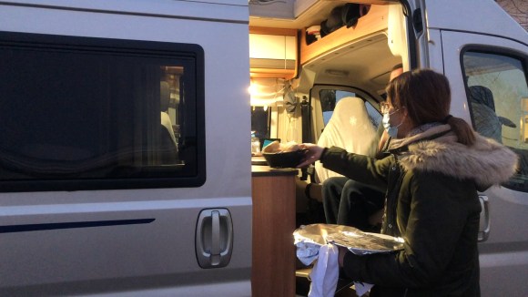 une restauratrice sert un plat à un camping-car