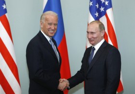 مصافحة بين بايدن وبوتين أمام أعلام روسيا وأمريكا