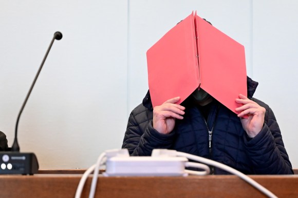 Man covers head in court with file