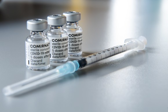 three small bottles of vaccine and a syringe