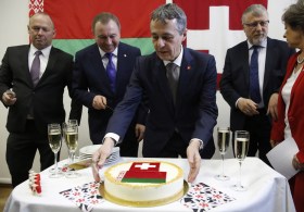 رجال وامرأة يحيطون بحلوى رسم عليها علما سويسرا وبيلوروسيا