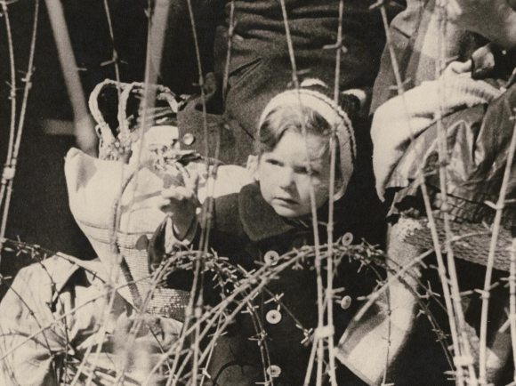 Старинная фотография ребенка за колючей проволокой.